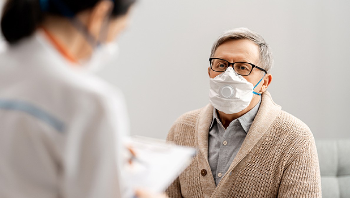 Man wearing a mask listening to female doctor