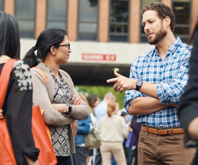 Two colleagues are talking outside of a building.